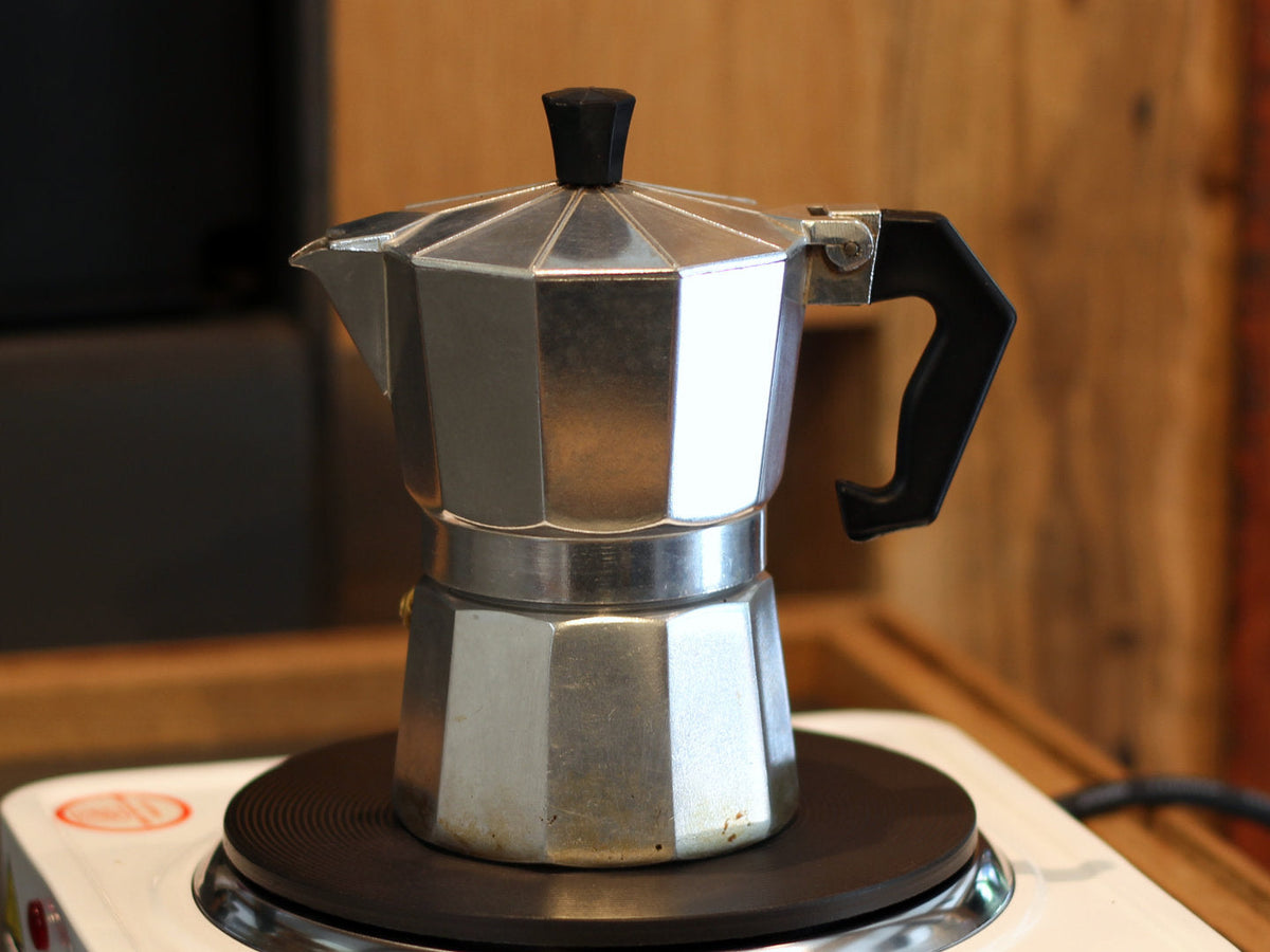 Titelbild zum Artikel über die Kaffeezubereitung mit dem Espressokocher. Zu sehen ist ein typischer achteckiger Espressokocher aus Aluminium auf einer Herdplatte.